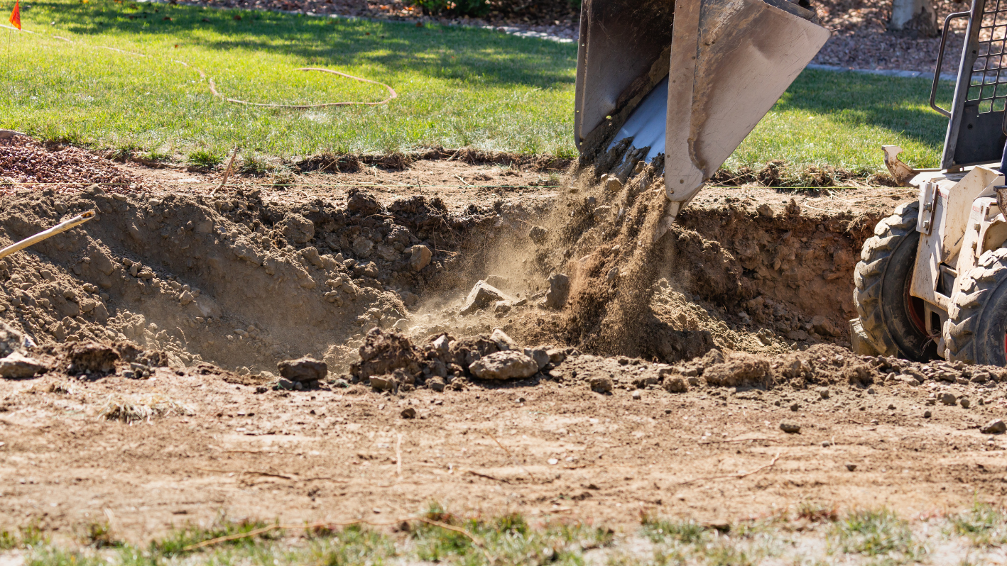 A man digging dirt in a yard with a tractor