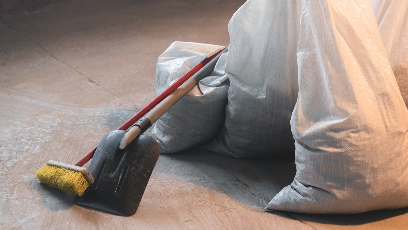 A broom and dust bag sitting on the ground