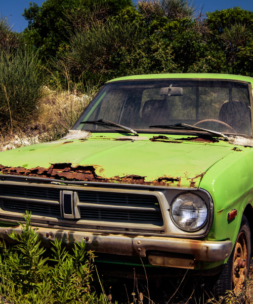 An old green truck sitting in a field